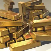 سبائك ذهب لامعة متراصة فوق بعضها على سطح فاتح