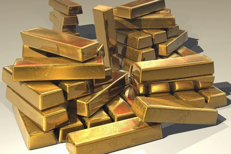سبائك ذهب لامعة متراصة فوق بعضها على سطح فاتح